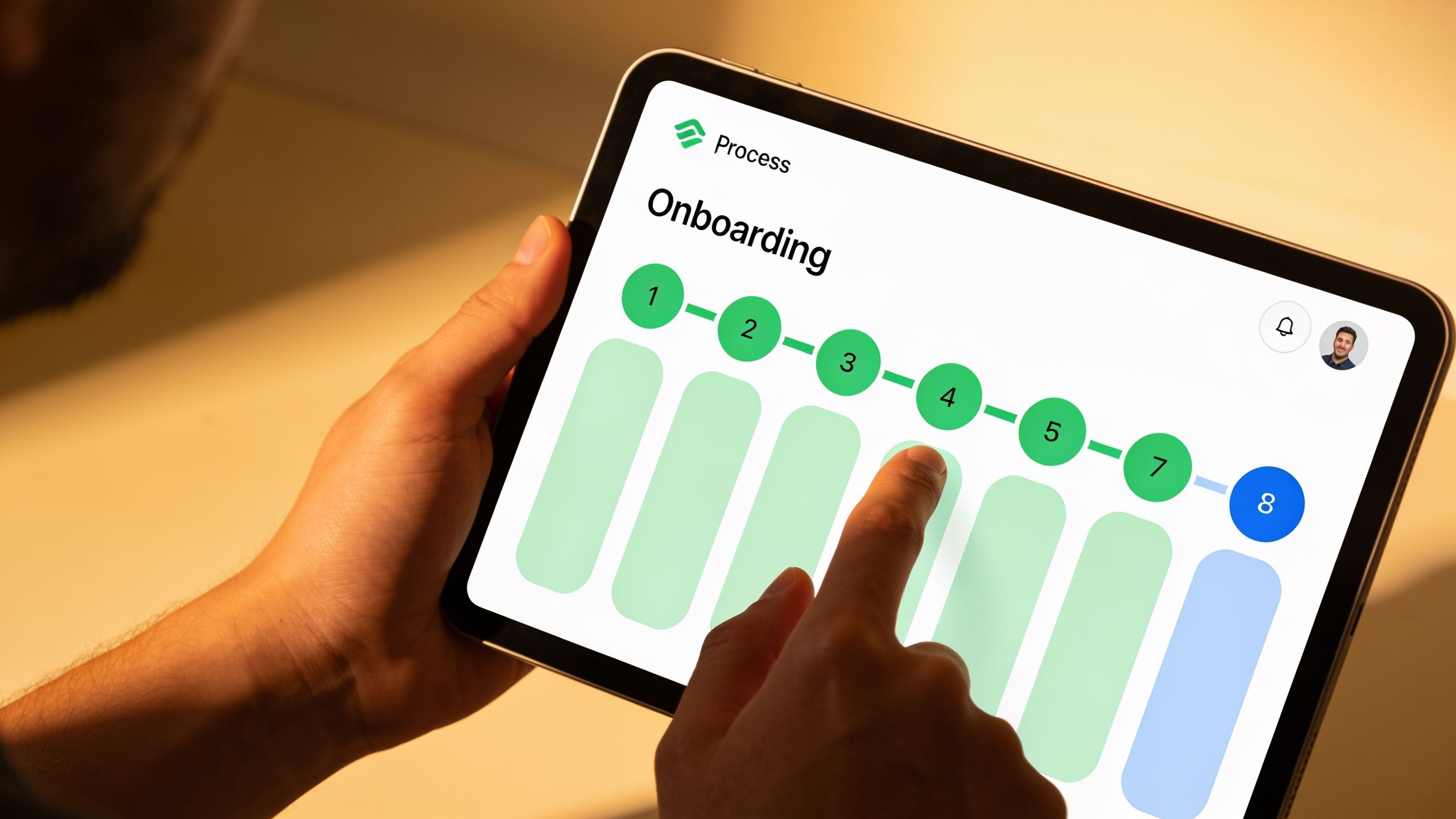 Hands interact with a tablet displaying an onboarding progress bar on a clean, modern interface.